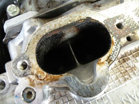 1998 Subaru Legacy - Exhaust manifold port showing significant carbon buildup and residue.