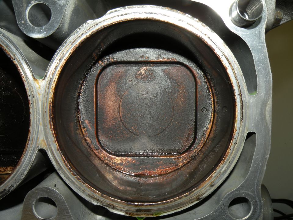 Close-up of an engine cylinder bore showing carbon buildup on the piston top