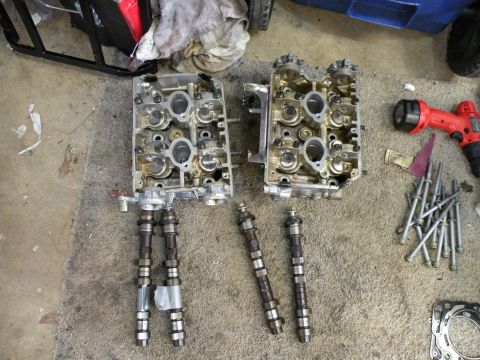 1998 Subaru Legacy - Disassembled engine components, including cylinder heads and camshafts, are shown on a workshop floor.