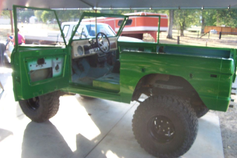 Green 1976 Ford Bronco with doors open, undergoing restoration