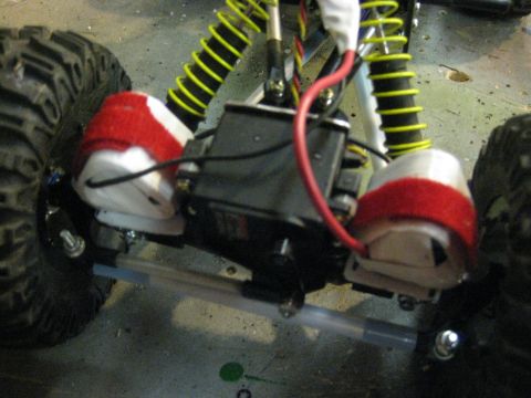 2010 Ford Pickup - Close-up view of a remote control car's chassis, highlighting the suspension system with yellow springs and red decorative elements.