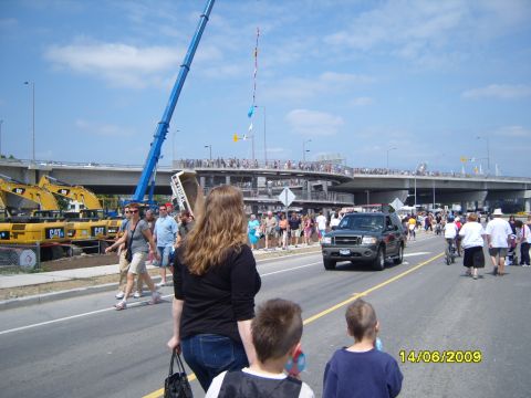 1989 Ford Bronco - A dark SUV drives down a street lined with pedestrians and construction equipment under a bright sky.