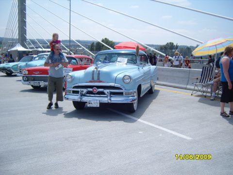 1989 Ford Bronco - A light blue convertible is displayed at a car show on a sunny day.