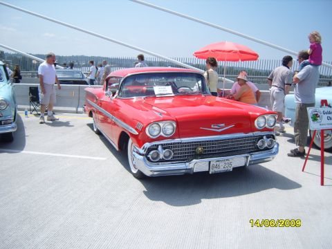 1989 Ford Bronco - A red 1958 Chevrolet Bel Air convertible is displayed at an outdoor car show.