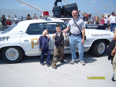 1989 Ford Bronco - A family poses with a vintage police car, which has a large spotlight mounted on the roof.