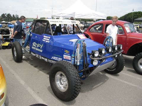 1986 Ford Bronco - Custom blue buggy with racing stickers parked next to a red Volkswagen Beetle.