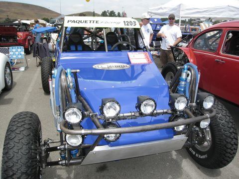 1986 Ford Bronco - This custom buggy features a roll cage, multiple spotlights, and off-road tires, parked next to a classic red VW Beetle.