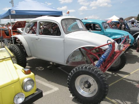 1986 Ford Bronco - This heavily modified VW Beetle, built for off-roading, is displayed at an outdoor car show with other vehicles.