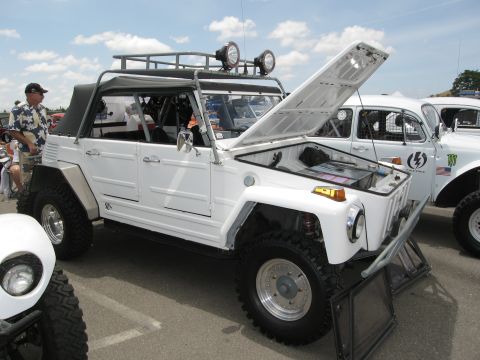 1986 Ford Bronco - A white off-road vehicle is displayed with its hood open, parked next to other vehicles under a cloudy sky.