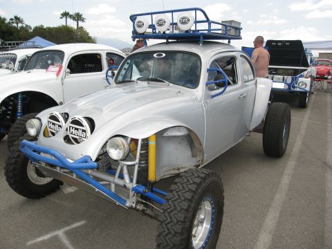 1986 Ford Bronco - Modified Volkswagen Beetle with off-road tires and suspension, parked at an outdoor event with other vehicles.