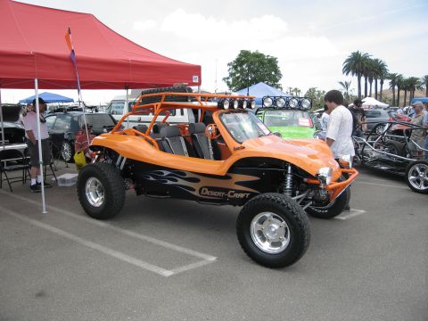 1986 Ford Bronco - An orange dune buggy with flame decals and a roof rack is displayed at an outdoor event.