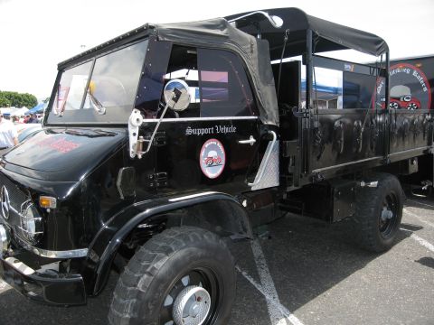 1986 Ford Bronco - This black Mercedes-Benz Unimog truck is a support vehicle with a canvas top and a flatbed.