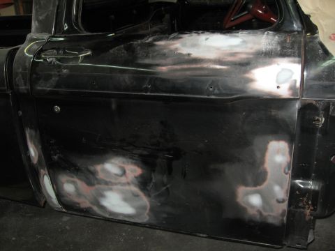 1966 Ford F-100 - Door panel of a 1966 Ford F-100 undergoing bodywork, with visible filler and primer.