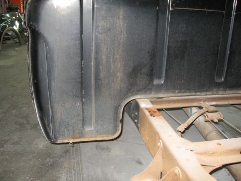 1966 Ford F-100 - Detail of a truck's rear corner and chassis, showing the bed's lower edge and frame structure.