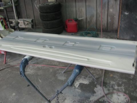 1966 Ford F-100 - A white Ford tailgate is shown on a stand in a workshop, ready for paint or repair.