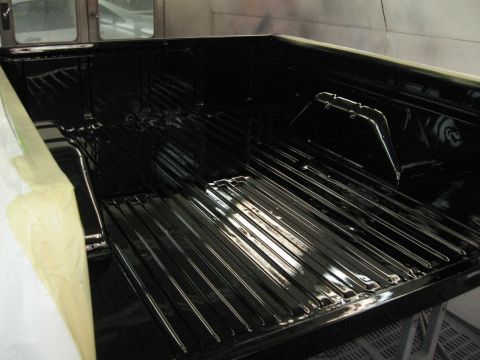 1966 Ford F-100 - The freshly painted black truck bed shows ribbed flooring and taped edges, suggesting recent body work.