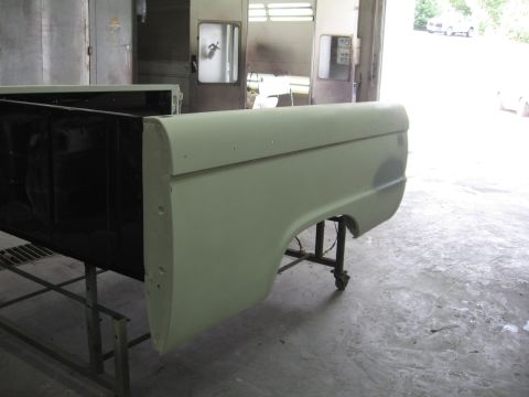 1966 Ford F-100 - A light green 1966 Ford F-100 truck bed side panel is shown on a stand in a body shop, likely awaiting further work.
