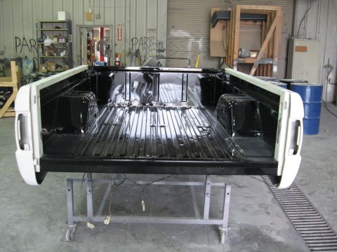 1966 Ford F-100 - The interior of a truck bed, recently painted black, is shown on a stand in a workshop.
