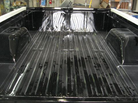 1966 Ford F-100 - The glossy black finish of this truck bed is visible from a rear-facing angle.
