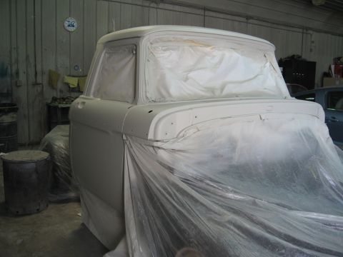 1966 Ford F-100 - A truck is being prepped for painting in a body shop, with plastic sheeting covering most of its exterior.