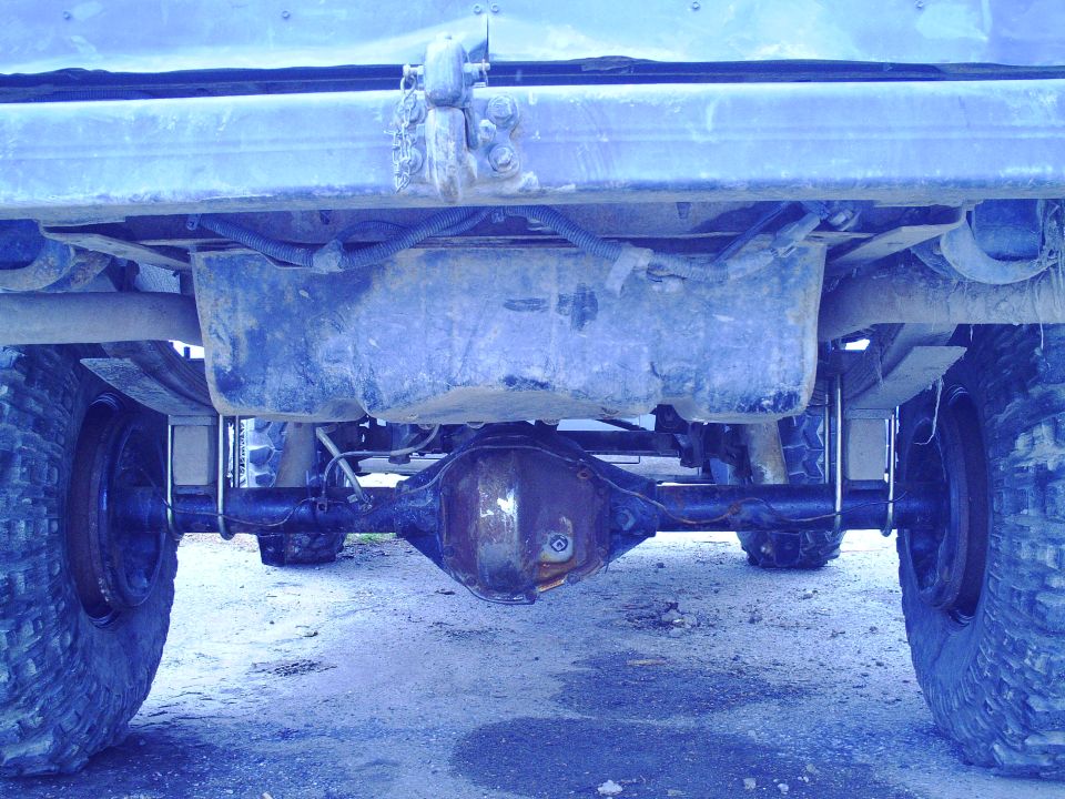 Rear differential and fuel tank assembly of a truck. Leaf springs and tires are visible
