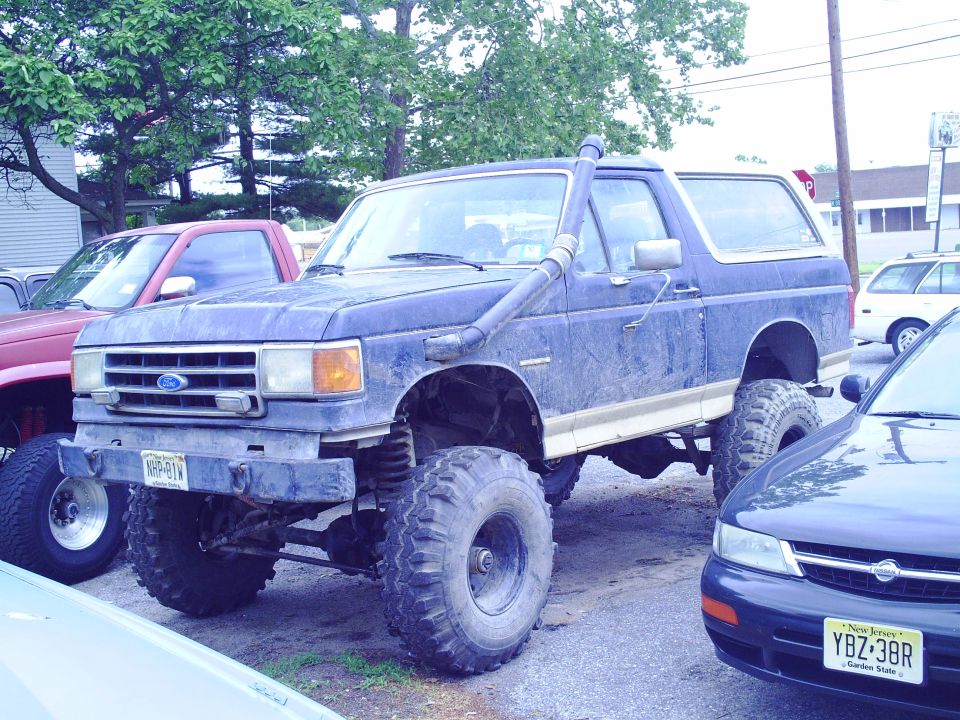 Blue Ford Bronco with snorkel, lifted suspension, and large tires