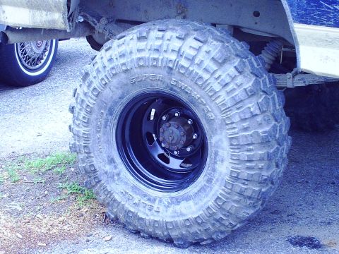 1990 Ford Bronco - Close-up of a large, aggressive off-road tire and suspension components on a vehicle.