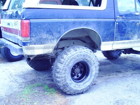 1990 Ford Bronco - The rear of a blue Ford Bronco shows off its large tires and off-road modifications.