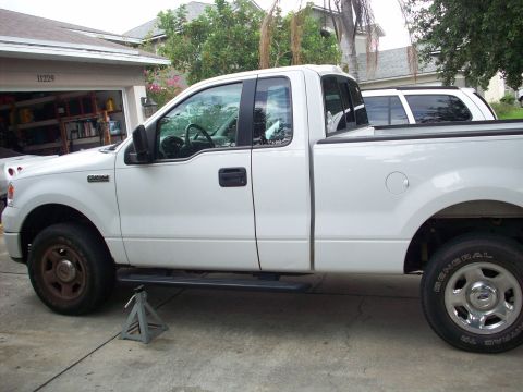 2006 Ford F-150 - White 2006 Ford F-150 pickup truck on jack stands with a second vehicle behind it.