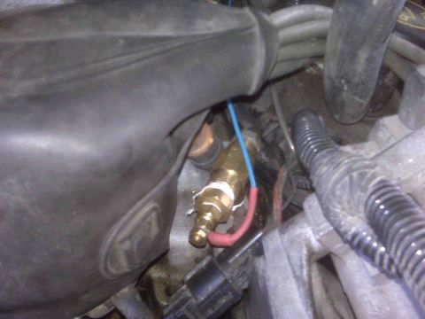 1995 Ford Bronco - A close-up view of a brass sensor with electrical connections, likely part of the engine's sensor system.