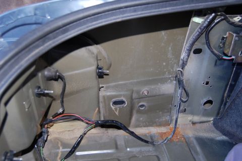 1985 Mercury Grand Marquis - Close-up of the inside of a car's trunk, revealing wiring harnesses and signs of rust.