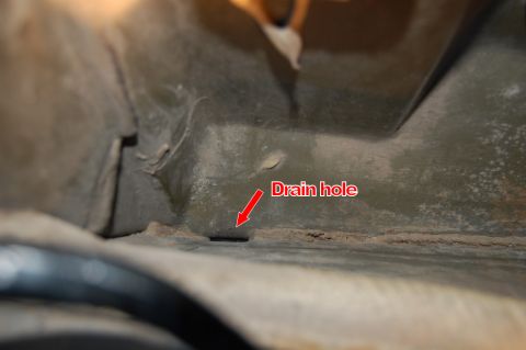 1985 Mercury Grand Marquis - A close-up view of a trunk floor reveals a drain hole, but no specific vehicle year or model can be identified.