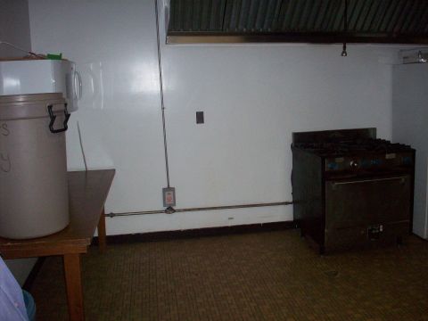 1985 Ford Bronco - Interior of a commercial kitchen a gas stove and a large storage container.