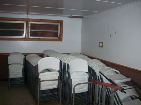 1985 Ford Bronco - A room is filled with rows of stacked white chairs, ready for an event.