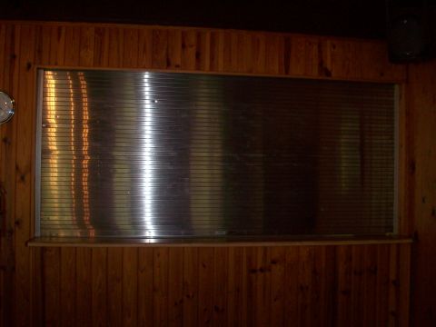 1985 Ford Bronco - A window covered by blinds is set into a wood-paneled wall above a counter.