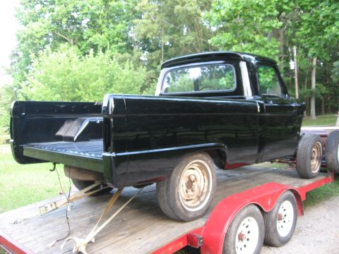 1966 Ford F-100 - This black pickup truck, likely a 1961 Ford F-100, is being transported on a red trailer.
