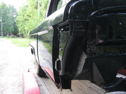 1966 Ford F-100 - The side of a black 1966 Ford F-100 pickup truck, viewed from the rear quarter, is shown on a trailer.