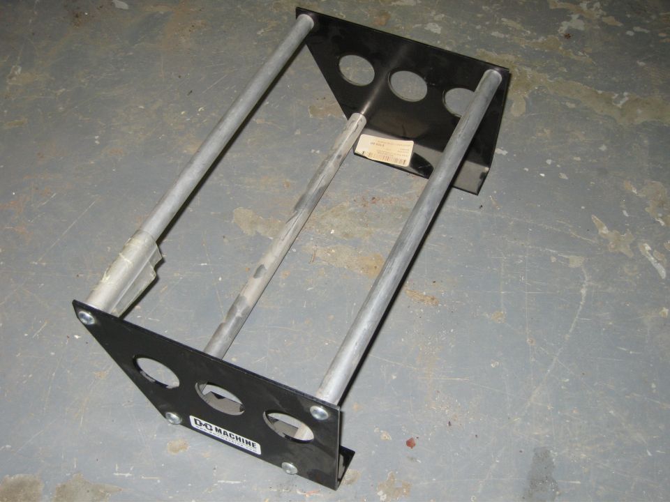 Fabricated bracket with black end plates and three metal tubes, D-C Machine sticker, on concrete floor