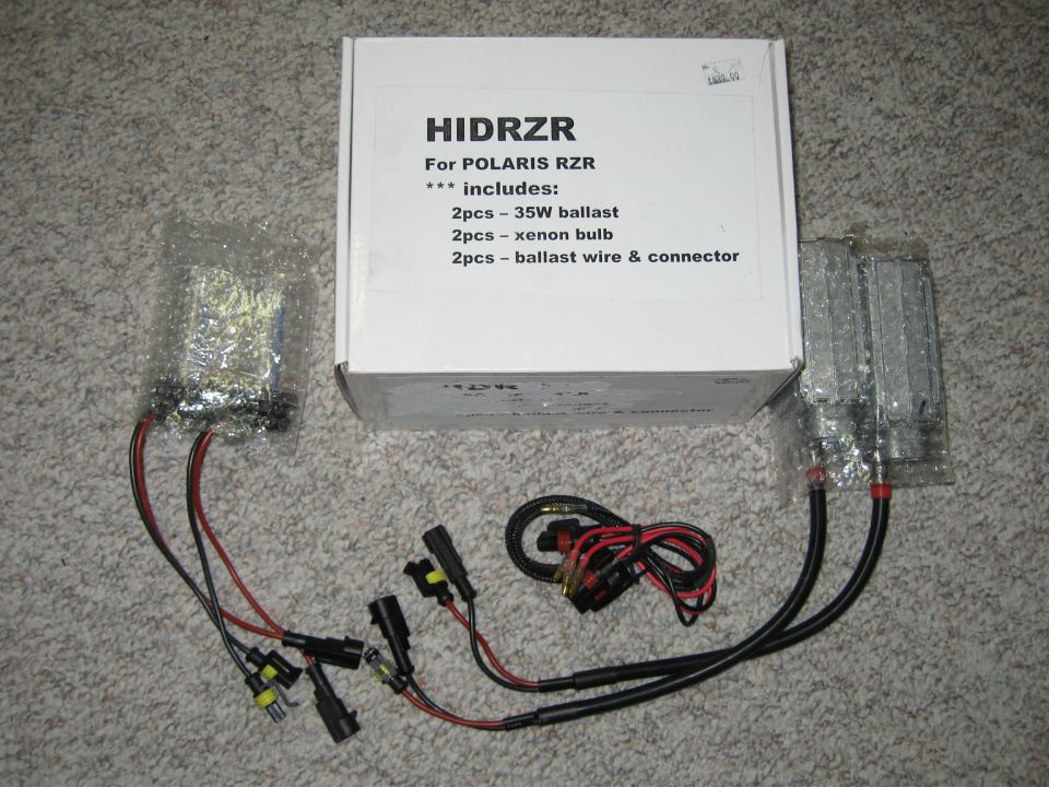 HID headlight conversion kit with ballasts, xenon bulbs, and wiring harnesses beside HIDRZR Polaris RZR box