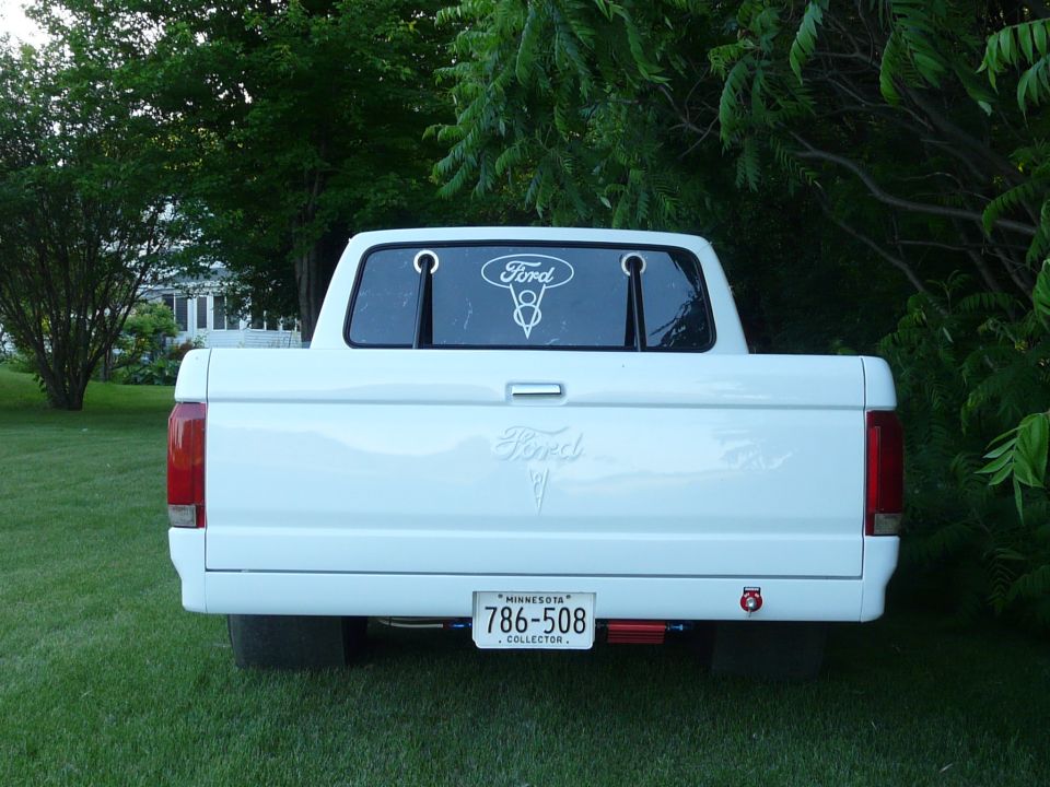 Rear view of a white Ford pickup on grass with Minnesota collector plate 786-508