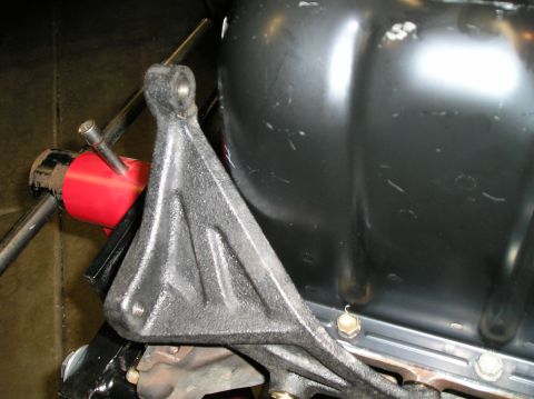 1986 Toyota Hilux - Close-up of an engine mount bracket bolted to a black oil pan, with a red engine hoist adapter visible.
