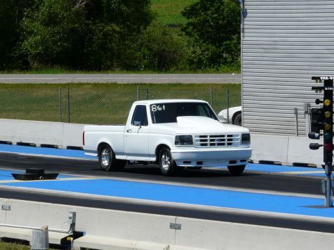 1994 Ford F-150 - White Ford regular-cab short-bed pickup staged at the starting line of a drag strip, wearing '861' in white shoe polish on the windshield a…