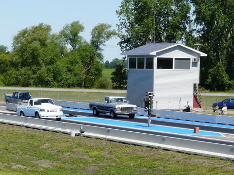 1994 Ford F-150 - Two Ford pickups staged side by side at a drag strip starting line, a white one numbered 861 in the left lane and an older dark blue and wh…