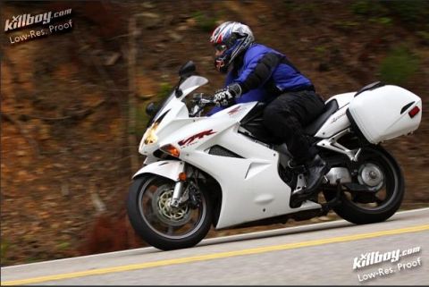 1985 Ford LTD Crown Victoria - A rider on a white sportbike navigates a road with wooded scenery.