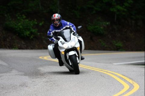 1985 Ford LTD Crown Victoria - Rider navigates a curve on a white touring motorcycle, with saddlebags attached.