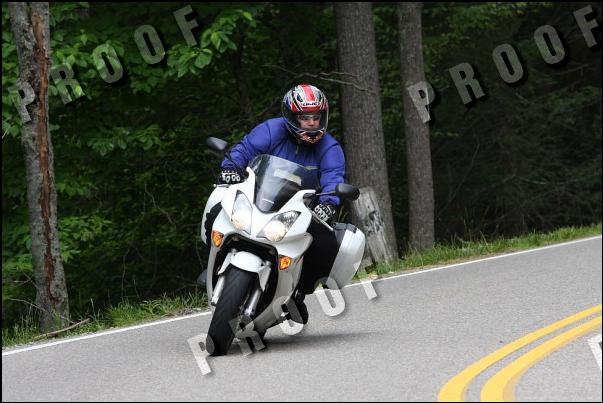 White motorcycle with saddlebags leaning into a turn on a paved road