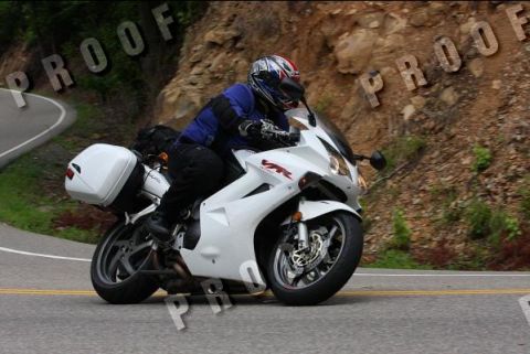 1985 Ford LTD Crown Victoria - Rider on a white sportbike navigates a curve on a mountain road.