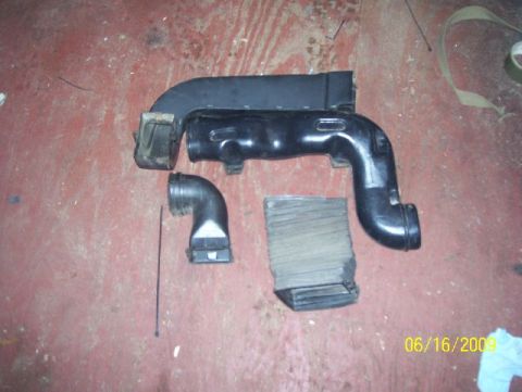 1978 Ford Bronco - Air intake components, including ducting and a filter, are laid out on a red floor. The image is dated 06/16/2009.