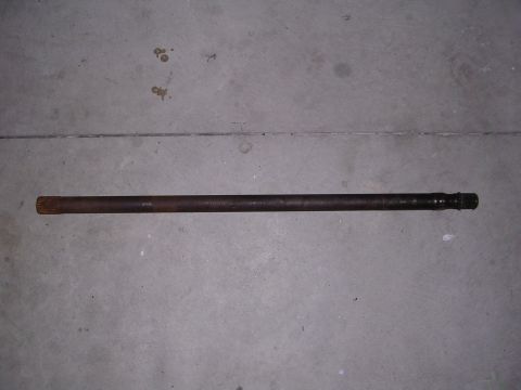 1983 Ferrari Enzo - A single drive shaft lies horizontally on a concrete surface, showing signs of wear and age.