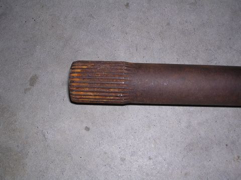 1983 Ferrari Enzo - A close-up view of a rusted axle shaft, showing its splined end resting on a concrete floor.